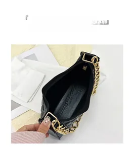 Detail view of black quilted leather crescent bag showing interior zip and gold chain strap