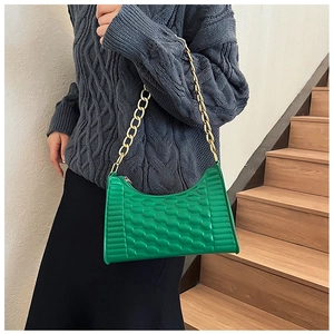 Detail of green crescent bag with honeycomb texture and gold chain strap on model
