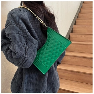 Detail of green crescent underarm bag with checkered embossing and gold chain strap