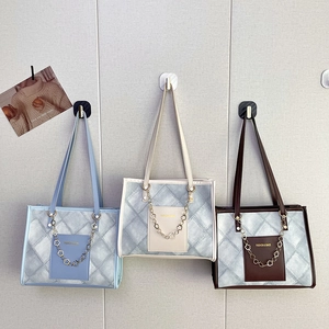 Three elegant quilted tote bags in blue, cream, and brown hanging on a minimalist wall