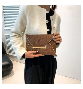 Dettaglio di una pochette in pelle intrecciata marrone con elegante bordo in metallo dorato
