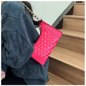Detail of vibrant pink crescent bag with hexagonal texture and gold metal chain strap
