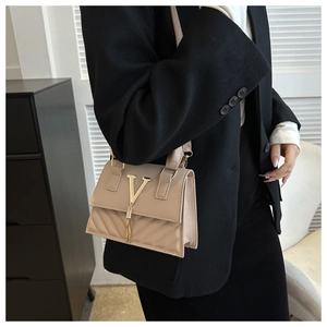 Dettaglio della borsa beige trapuntata con decorazione a V dorata e nappa lunga a frange