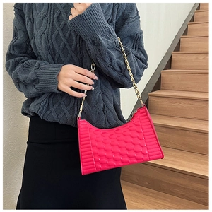 Detail of fuchsia crescent bag with embossed heart patterns and gold chain strap