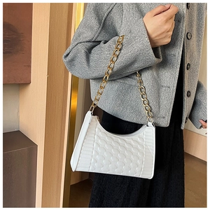 Detail of white quilted crescent bag with chunky gold chain strap worn by a model