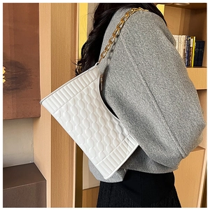 Detail of white crescent bag with textured geometric pattern and gold chain strap