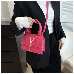 Dettaglio borsa trapuntata rosso rosa con logo V dorato e nappa su blazer nero