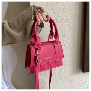 Detail of rose red quilted handbag featuring gold metal hardware and smooth faux leather texture