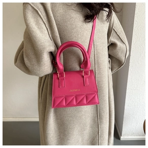 Detail showing fuchsia handbag with geometric quilted pattern on beige winter coat