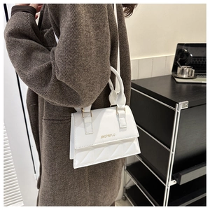 Detail showing white quilted leather texture and golden logo on the crossbody handbag