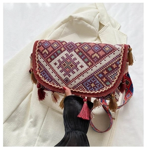 Détail de broderie géométrique sur sac bandoulière bordeaux avec glands décoratifs