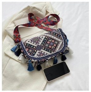 Détail du sac bohème avec des pompons colorés et des motifs tissés ethniques sur veste