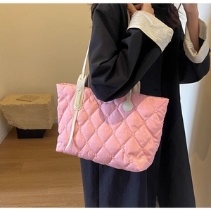 Detailansicht einer rosa gesteppten Shopper-Tasche mit weißen Lederriemen am Modell