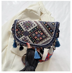 Détail d'un sac bandoulière bohème tissé avec motifs colorés et breloques à pompons