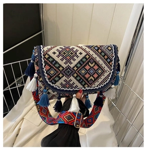 Détail d'un sac bohème tissé avec motifs géométriques et pompons à franges bleues