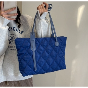 Détail macro du sac cabas matelassé bleu roi avec surpiqûres et fines bretelles