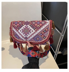 Détail d'un sac bandoulière bohème tissé avec motifs géométriques et glands rouges
