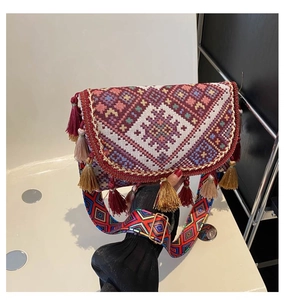 Gros plan détaillé d'un sac ethnique tissé avec de vibrants pompons rouges et dorés
