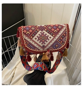 Détail des broderies ethniques et pompons colorés sur un sac bandoulière bohème chic