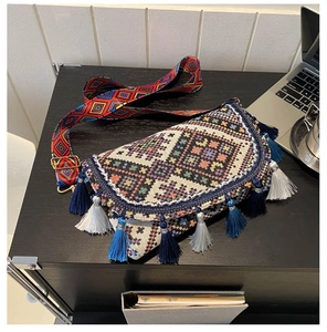 Détail de sac bandoulière ethnique tissé avec pompons bleus et sangle à motifs géométriques