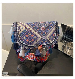Détail d'un sac bandoulière ethnique avec pompons bohèmes et sangle en jacquard