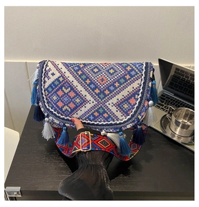 Détail d'un sac à bandoulière tissé ethnique avec motifs géométriques et pompons bleus