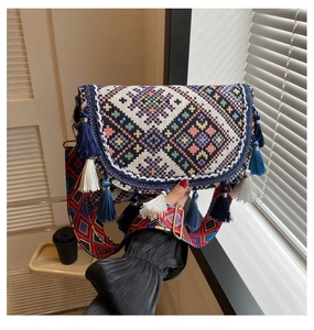 Gros plan sur un sac bohème tissé avec des pompons superposés et une bandoulière large