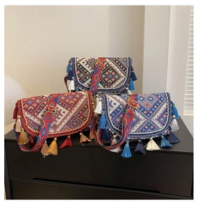 Détail de sacs bohèmes avec motifs géométriques tissés et pompons colorés faits main