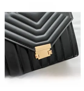 Close-up of black quilted leather texture and golden metal buckle on a shoulder bag