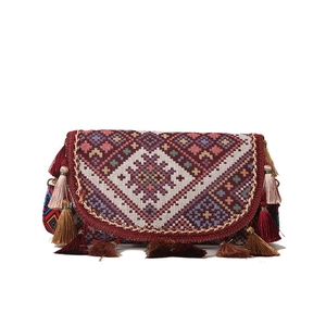 Vue détaillée de la broderie ethnique et des pompons colorés sur le rabat du sac