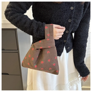 Close-up of strawberry print corduroy knot bag with minimalist handle detail