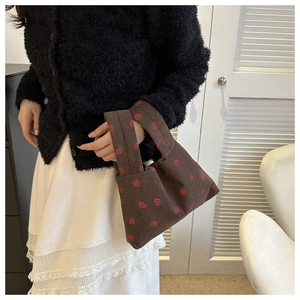 Detail of a brown corduroy tote bag featuring red strawberry prints and a single handle