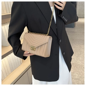Close-up of beige chevron quilted crossbody bag with gold chain and metal clasp