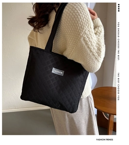 Close-up of black quilted tote bag with fashion label shown on a model for daily commute