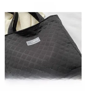 Detail of black quilted nylon tote bag with fashion label and diamond stitching