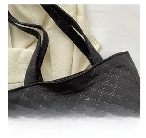 Detail of black quilted tote bag with white contrast stitching and Fashion patch