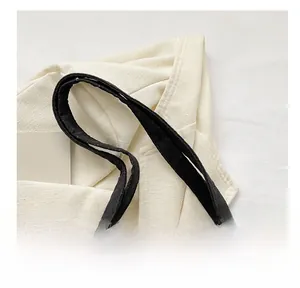 Detail of comfortable quilted handles on black nylon tote bag with diamond stitching