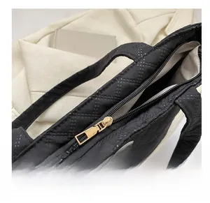 Detail of smooth gold zipper on black quilted tote bag with textile HION label