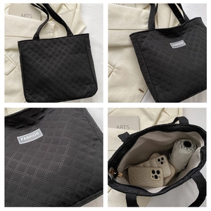 Detail view of large black quilted tote bag showing spacious interior and fashion logo