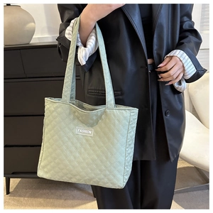 Close-up of mint green quilted tote bag with diamond pattern and fashion patch