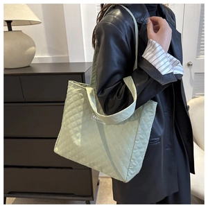 Quilted light green tote bag with diamond stitching and slim straps shown on a model