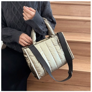 Close-up of champagne puffer bag with quilted texture and adjustable black woven strap