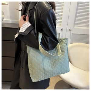 Close-up of light green quilted nylon tote bag with classic diamond stitching patterns