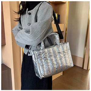 Detail of silver quilted crossbody bag featuring metallic finish and black woven strap