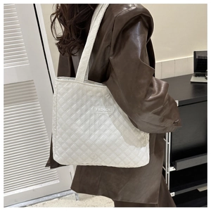 Close-up of white quilted tote bag with FASHION label and crossbody strap texture