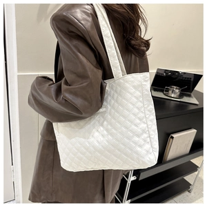 Detail of white quilted tote bag featuring fashion label and large capacity storage
