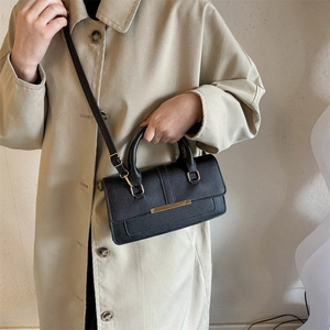 Elegant black lychee leather handbag with gold metal bar and adjustable shoulder strap