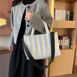 Chic silver quilted puffer tote bag with black strap shown in a lifestyle indoor setting