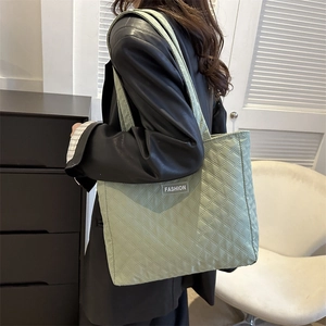 Green quilted tote bag with diamond stitching and fashion label for daily commute