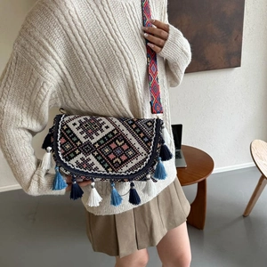 Sac bandoulière brodé ethnique avec pompons et large sangle à motifs sur mannequin